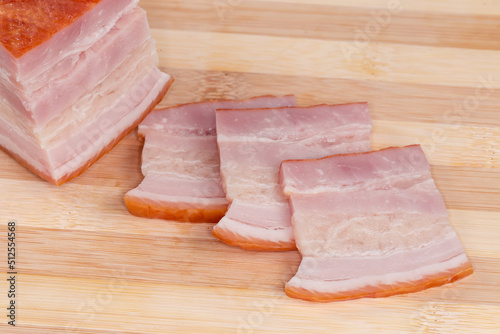 Slices of boiled smoked pork belly on a cutting board