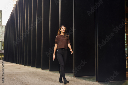 Young businesswoman walking on street with phone