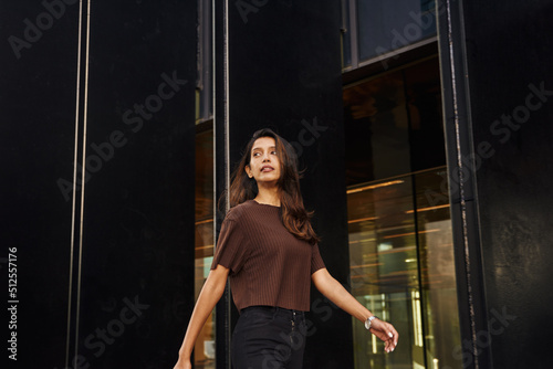 Stylish businesswoman walking on street with phone