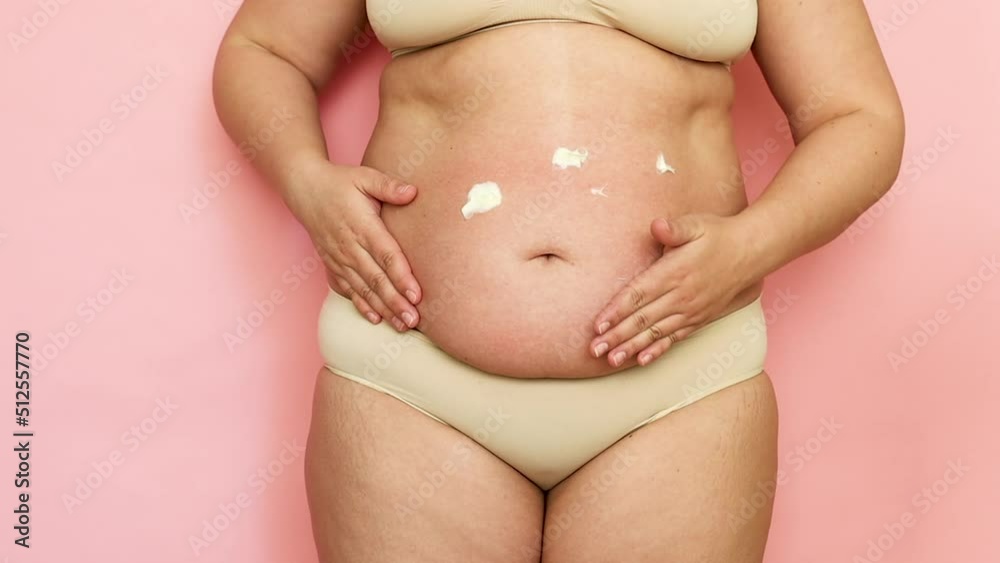 custom made wallpaper toronto digitalUnrecognizable fat woman in beige underwear applying white strokes of cream lotion on sagging cellulite belly at pink home studio White moisturizing cream lotion, rubbing treatment for dry skin. 
