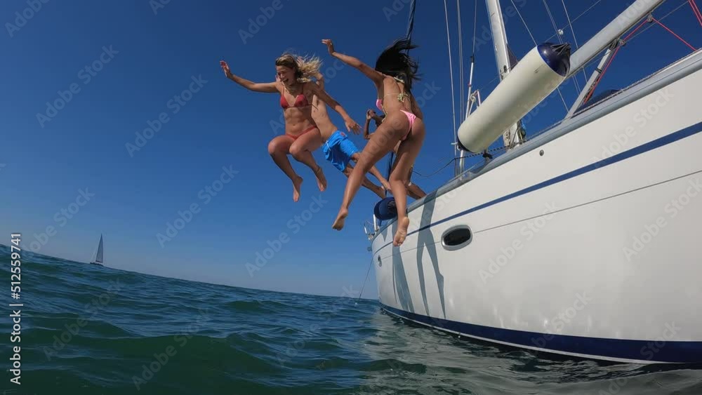 Happy multiracail friends diving from sailing boat into the sea