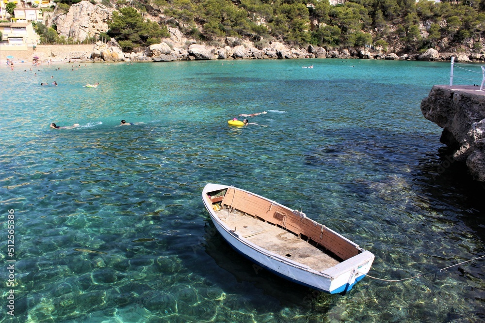Lonely boat floating on crystal clear water. Mallorca, Spain. 