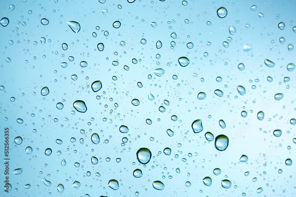Rain outside the window. Water droplets on a car glass on a background of blue sky and green grass. Overcast. Wet clean nature, ecology Rain outside the window. Water droplets on a car glass on a background of blue sky and green grass. Overcast. Wet clean nature, ecology
