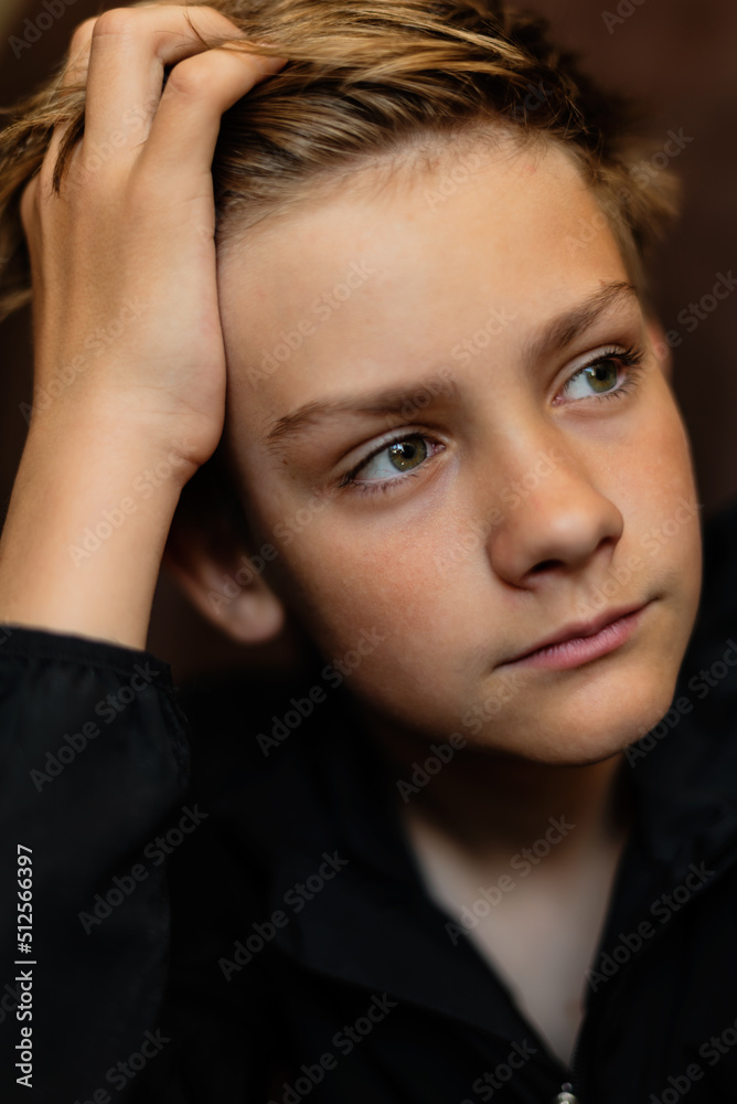 Portrait of blonde teenage boy on dark background outdoor. Low key close up shot of a young teen boy, adolescence. Selective focus. Loneliness, sadness, adolescent anxiety, emotional Portrait of blonde teenage boy on dark background outdoor. Low key close up shot of a young teen boy, adolescence. Selective focus. Loneliness, sadness, adolescent anxiety, emotional