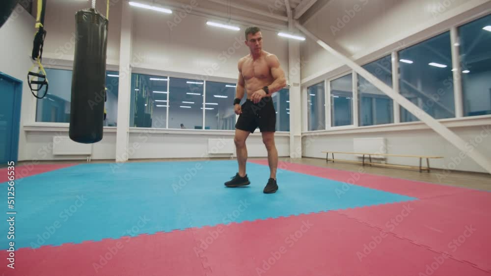 Handsome young muscular man with naked torso is training in a modern sports club and doing a back flip