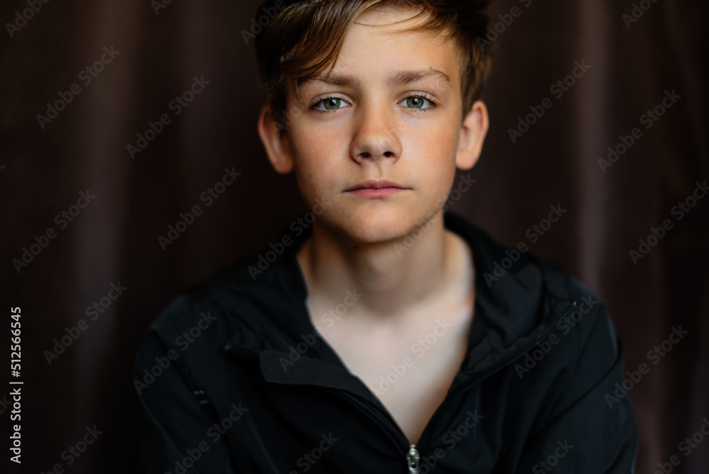 Portrait of blonde teenage boy on dark background outdoor. Low key close up shot of a young teen boy, adolescence. Selective focus. Loneliness, sadness, adolescent anxiety, emotional Portrait of blonde teenage boy on dark background outdoor. Low key close up shot of a young teen boy, adolescence. Selective focus. Loneliness, sadness, adolescent anxiety, emotional