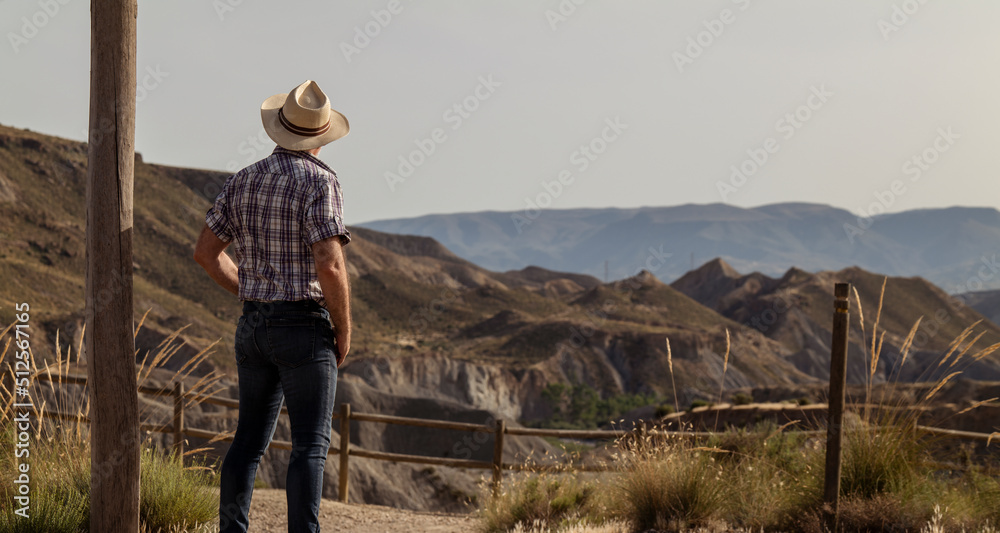 Rear view of adult man in sun hat and shirt in desert. Almeria, Spain Rear view of adult man in sun hat and shirt in desert. Almeria, Spain