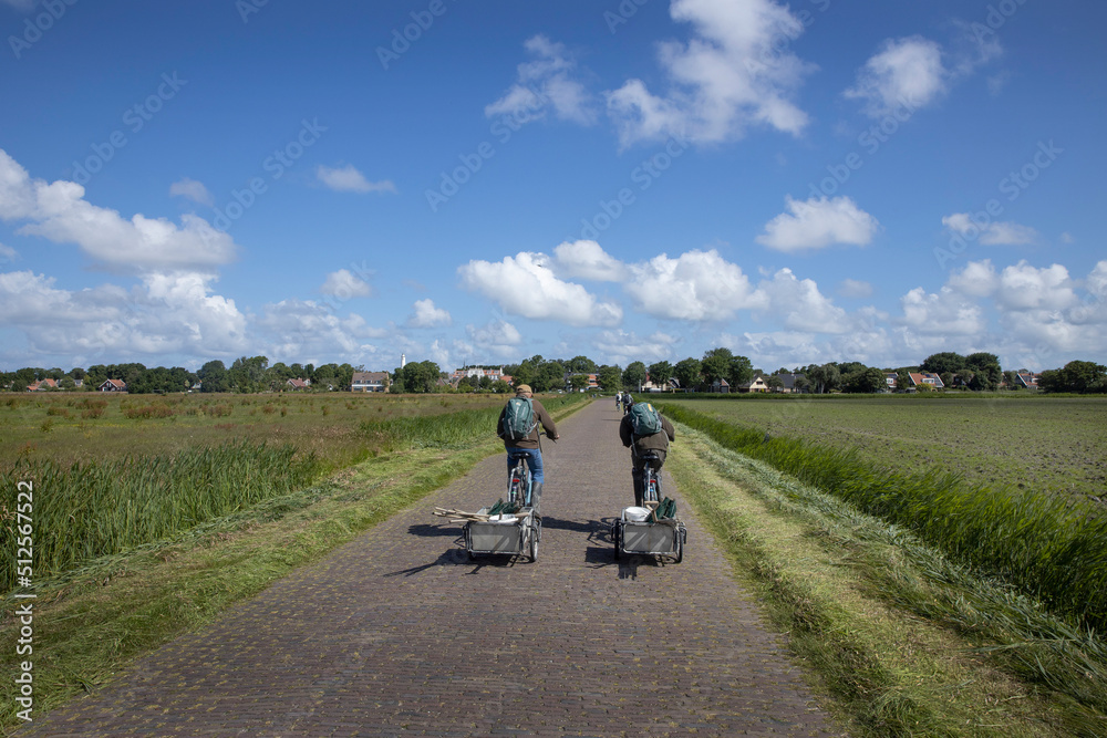 Cyclists at road to village. Schiermonnikoog waddeneiland. Netherlands. Waddenzee. Coast Cyclists at road to village. Schiermonnikoog waddeneiland. Netherlands. Waddenzee. Coast