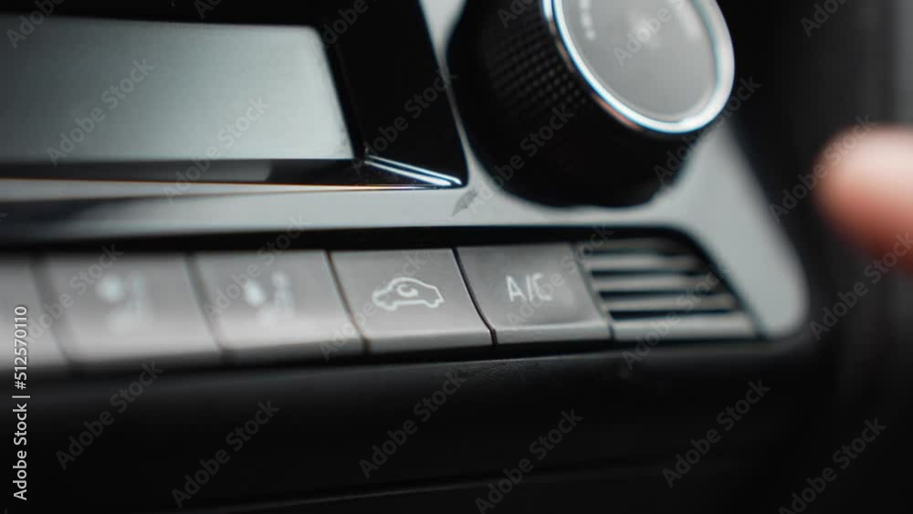 Closeup detail of finger activating air conditioning system, black buttons Closeup detail of finger activating air conditioning system, black buttons