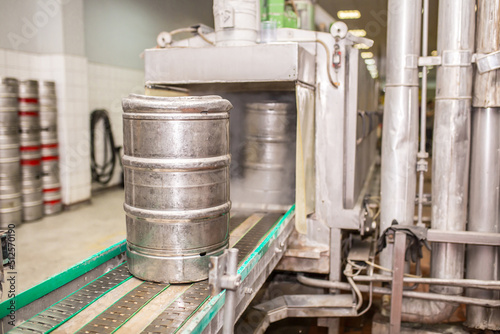 Brewery, bottling beer on aluminum kegs on conveyor lines. Industrial work, automated modern food and beverage production.