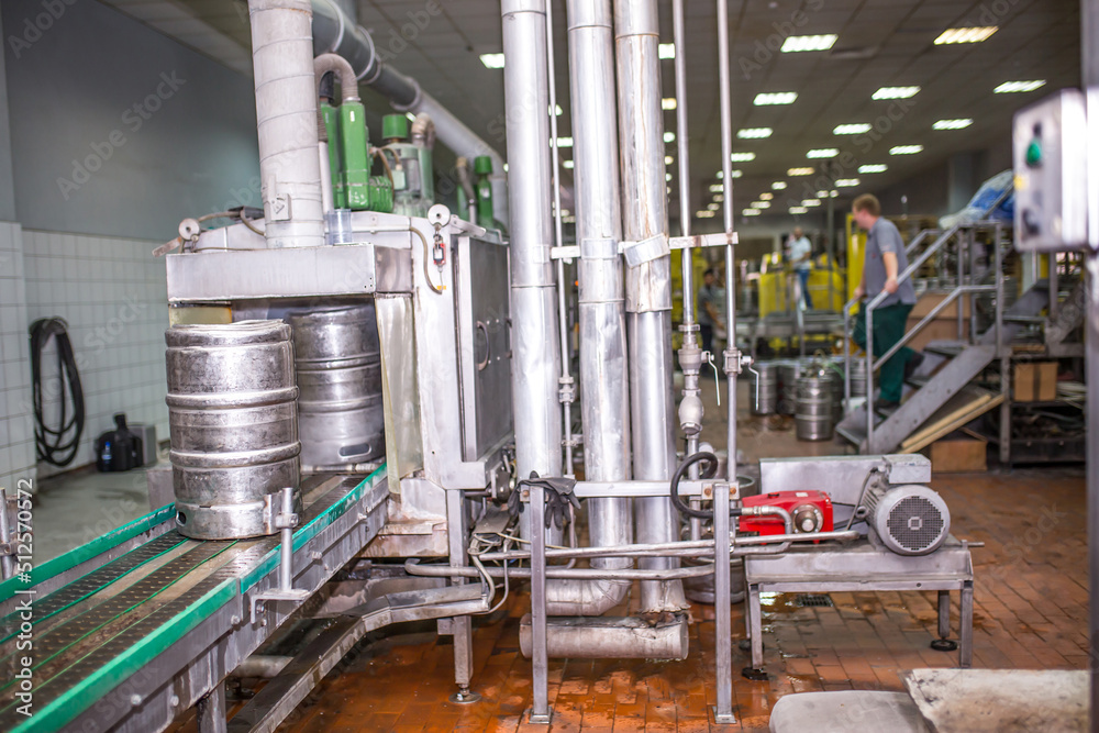 Brewery, bottling beer on aluminum kegs on conveyor lines. Industrial work, automated modern food and beverage production.