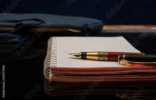 Diary and fountain pen on black office table