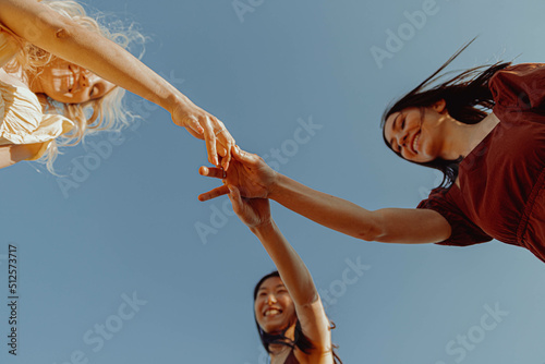 GIRLS HOLDING THEIR HANDS. VIEW FROM BELOW.  #512573717