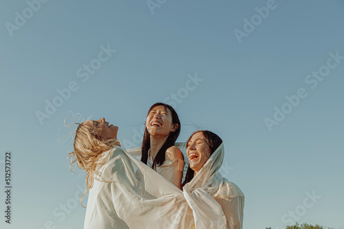 THREE HAPPY GIRLS ARE PLAYING WITH A FABRIC. photo