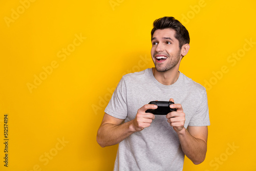 Photo of cute brunet young guy playstation look promo wear grey t-shirt isolated on yellow color background