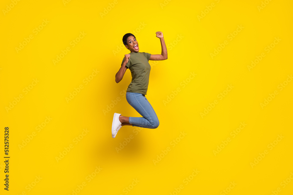 Full size portrait of delighted person jump raise fists celebrate triumph isolated on yellow color background