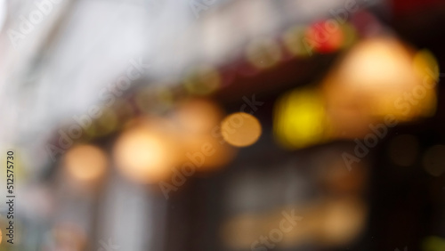 Blur background of European city street with bokeh of garlands, shop windows, cafe signboards