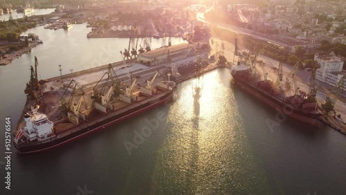 Aerial view of big cargo ship bulk carrier is loaded with grain of wheat in port at sunset