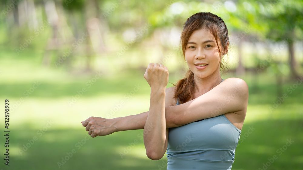 Healty Young female workout exercise before running or fitness training session in City Park. Healthy young woman warming up outdoors. She is stretching her arms at Garden park, Sports and activities Healty Young female workout exercise before running or fitness training session in City Park. Healthy young woman warming up outdoors. She is stretching her arms at Garden park, Sports and activities