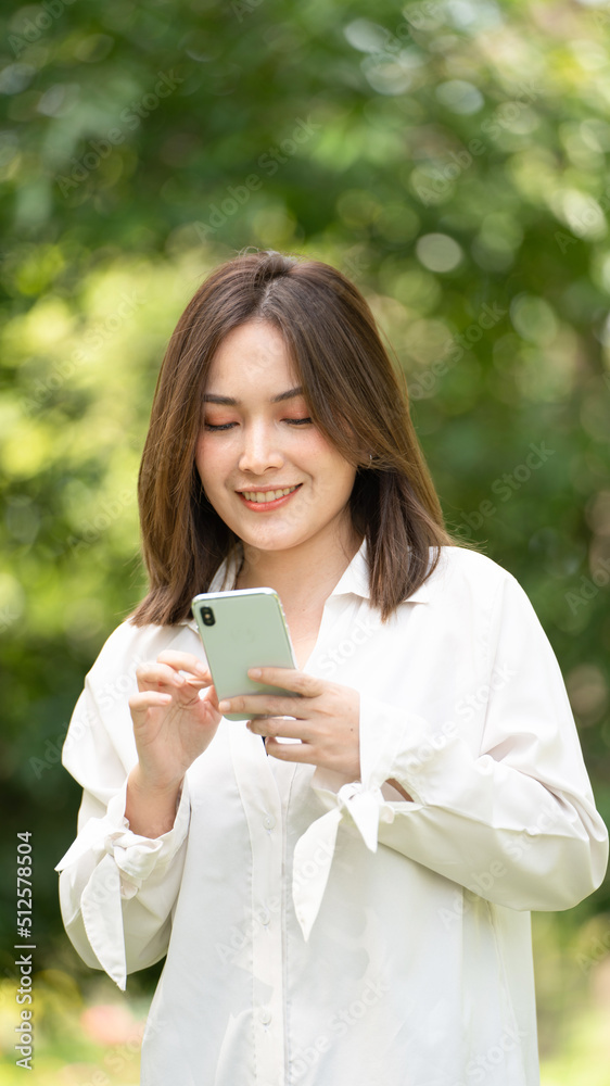 Thoughtful smile woman in park using smart phone, Portrait of a young charming business woman checking online Business work on her smart phone outdoors in the park on soft green back ground Thoughtful smile woman in park using smart phone, Portrait of a young charming business woman checking online Business work on her smart phone outdoors in the park on soft green back ground