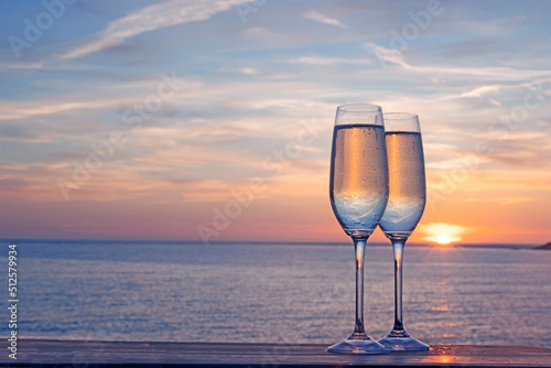 Pair of champagne flutes with prosecco in from of sunset in Woolacombe, North Devon, UK photo