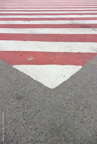 Vertical photo with down arrow. Red and white striped triangular road markings on asphalt, intended for the parking of fire equipment for use during a fire © brajianni