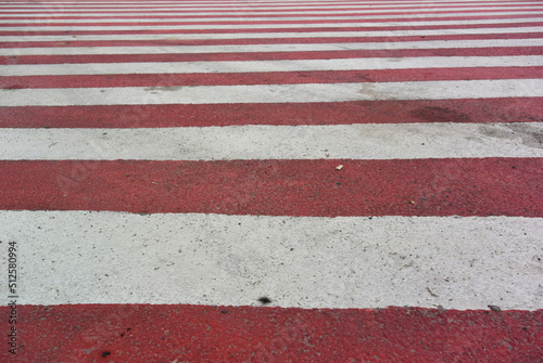 Pedestrian crossing with red and white horizontal stripes. Road markings on asphalt. Striped USA flag without stars © brajianni
