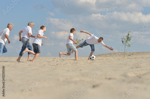 Family playing football on a beach in summer day