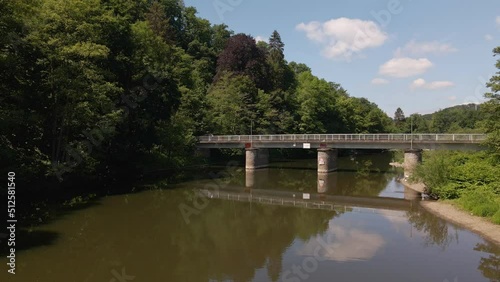 Car crossing a narrow bridge that reflects perfectly in the flat brown river water underneath. Static wide angle view on a sunny spring day in Germany photo