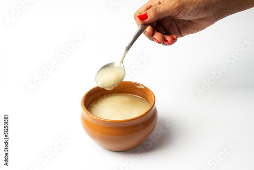 Pure cow ghee in ceramic bowl on white background with ghee spoon in hand photo