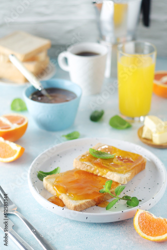 Sandwiches with marmalade, orange juice and coffee ready for breakfast