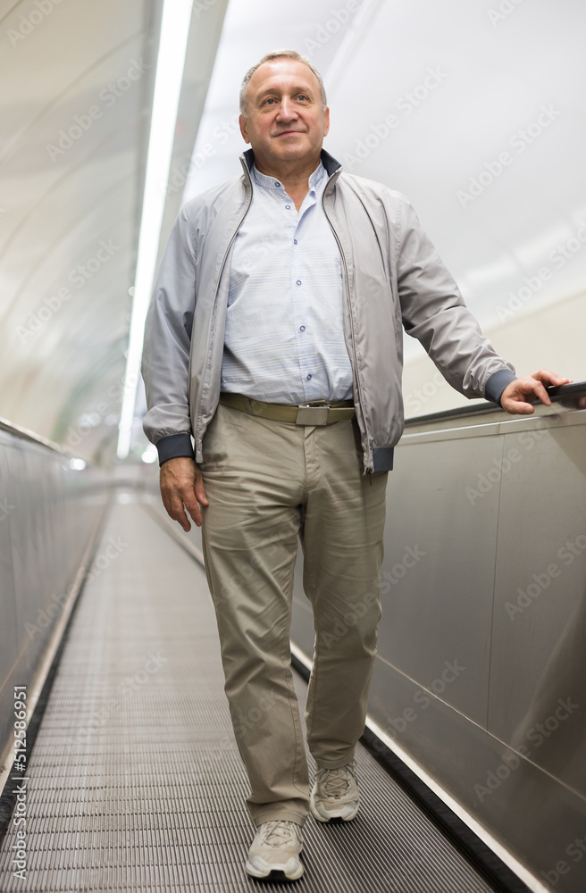 Senior passenger walks along travelator in an underground metro