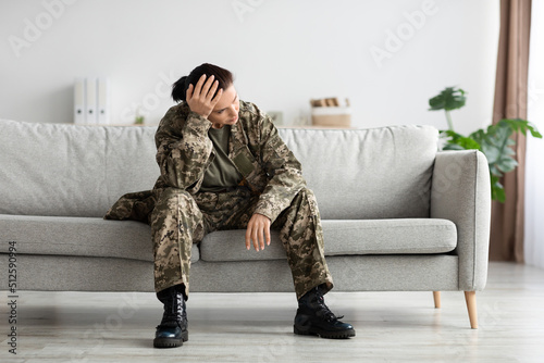 Mental Disorders In Military. Depressed Soldier Lady In Uniform Sitting On Couch © Prostock-studio