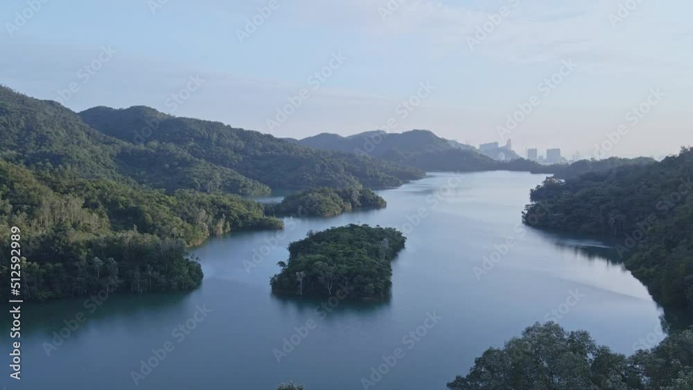 A dynamic ascending aerial shot of the mountains next to the dam and control tower of Shing Mun Reservoir in Hong Kong. It is located in Shing Mun, the area between Tsuen Wan and Sha Tin. A dynamic ascending aerial shot of the mountains next to the dam and control tower of Shing Mun Reservoir in Hong Kong. It is located in Shing Mun, the area between Tsuen Wan and Sha Tin.