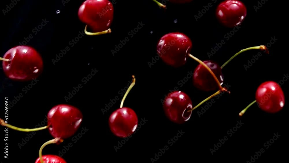 Close-up of the juicy red cherries are falling diagonally on a black background Close-up of the juicy red cherries are falling diagonally on a black background