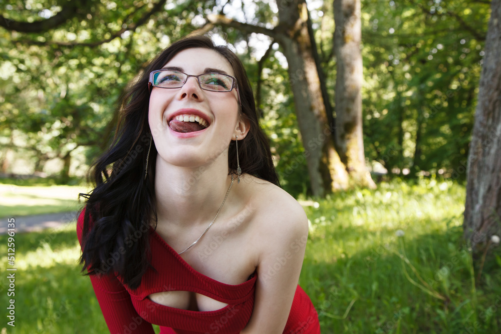 young brunette woman in a red dress walking in city park in summer young brunette woman in a red dress walking in city park in summer