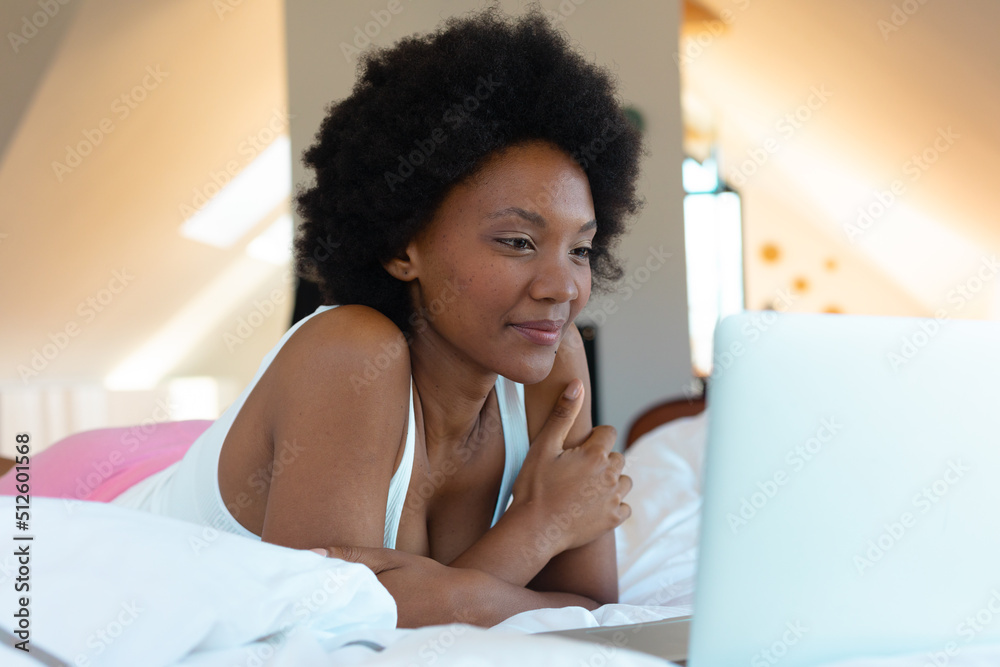 Afro young african american woman watching video on laptop in bedroom, copy space