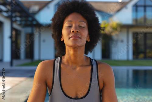 Afro african american young woman with eyes closed practicing yoga in backyard