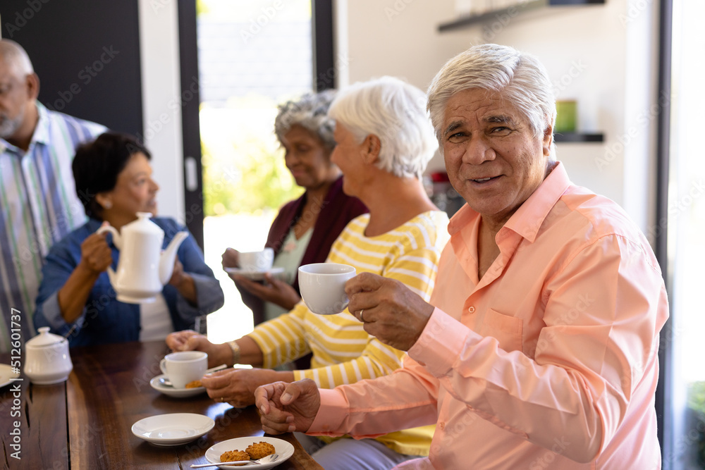 Portrait of biracial senior man having coffee and cookies with multiracial friends at table Portrait of biracial senior man having coffee and cookies with multiracial friends at table