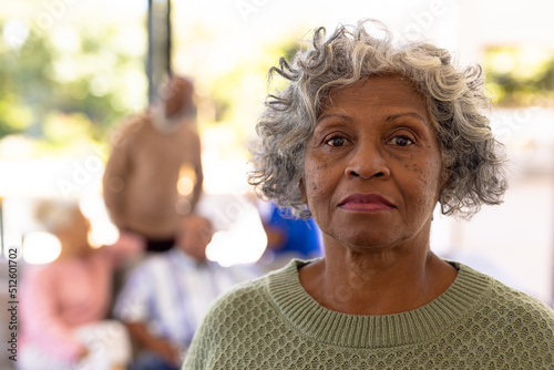 Close-up portrait of serious african american senior woman with multiracial friends in background