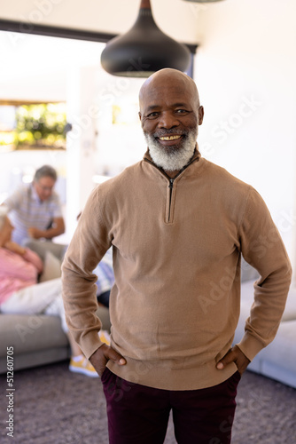 Portrait of smiling bald african american senior man with hands in pockets standing in nursing home