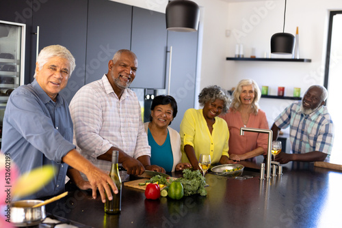 Portrait of happy multiracial senior friends making lunch on kitchen island at nursing home