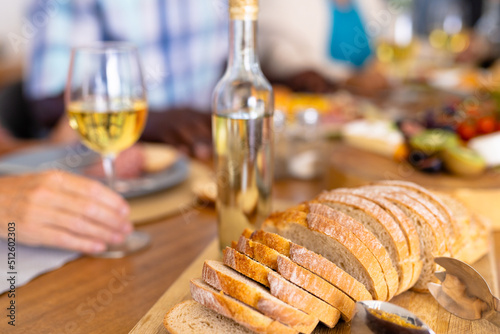 Close-up of bread slices on wooden board with white wine bottle on dining table in nursing home