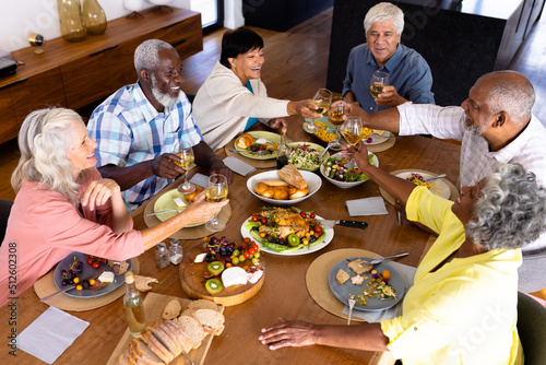 High angle view of multiracial senior friends toasting wineglasses at dining table in nursing home
