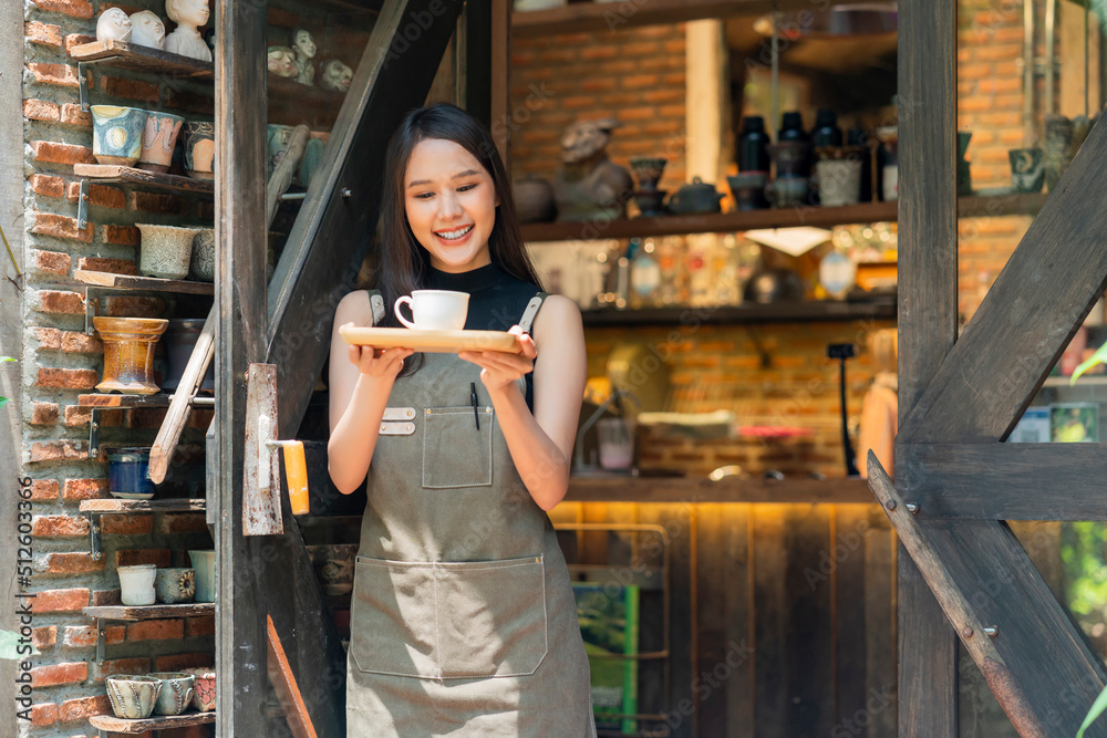 Portrait of a Asian Happy woman Standing In Front of his Coffee Shop hand serving present wooden tray with Cup of Coffee small business welcome reopen again,asian female smiling barista holding coffee