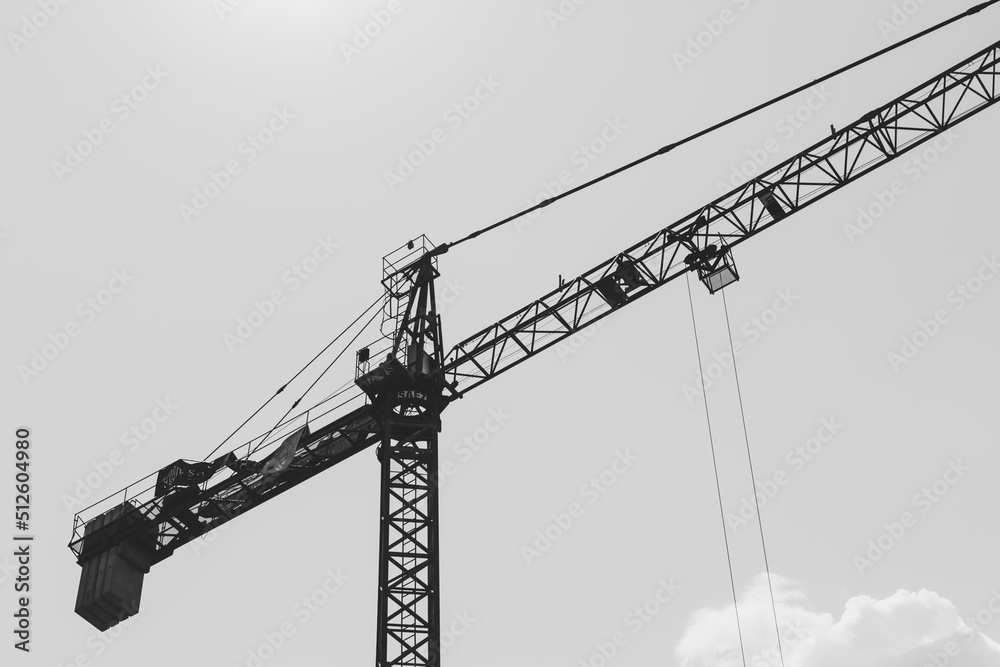 Black and white shot of a high construction crane against a clear sky Black and white shot of a high construction crane against a clear sky