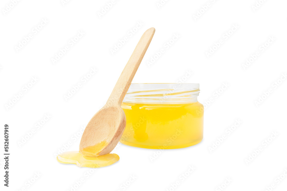 fresh yellow honey in a jar and next to a wooden spoon on a white background fresh yellow honey in a jar and next to a wooden spoon on a white background