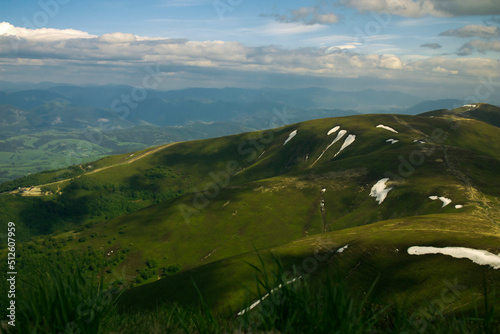 The horizon is at the height of the mountain range, the deep sky separates the green meadows.