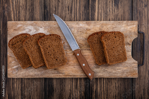 Fotobehang top view of rye bread slices and knife on cutting board on wooden background