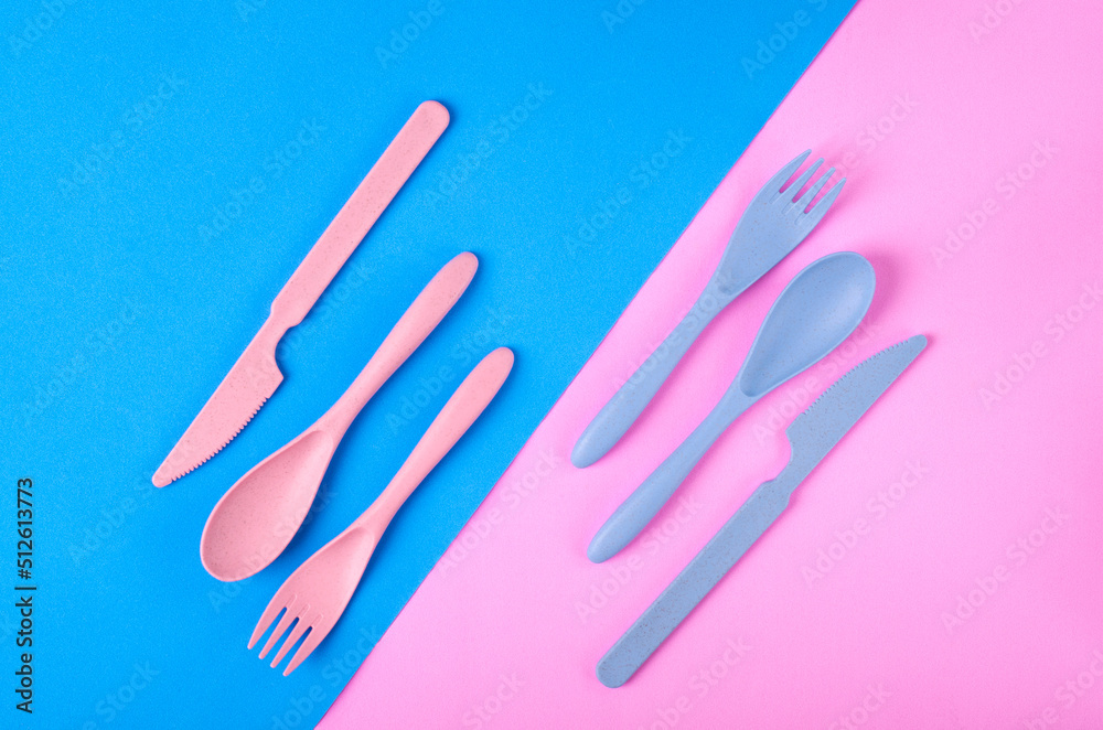 Cutlery set made of wheat straw of pink and blue colors on geometric background. Portable reusable utensils. School lunch concept. Flat lay Cutlery set made of wheat straw of pink and blue colors on geometric background. Portable reusable utensils. School lunch concept. Flat lay